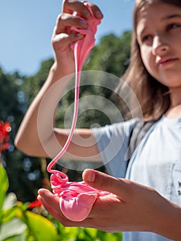 Girl playing with popular slime toy in a green park