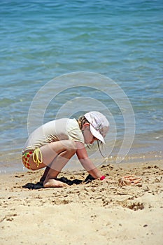 Girl playing on sand near sea during summer holidays. Summer vacations concept