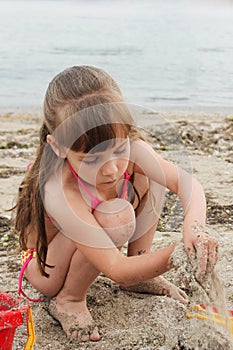 Girl playing with sand on the sea shore