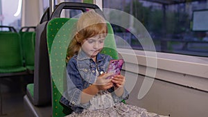 Girl playing on smartphone, chatting, texting, browsing social media while traveling by tram to city