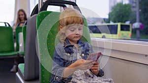 Girl playing on smartphone, chatting, texting, browsing social media while traveling by tram to city