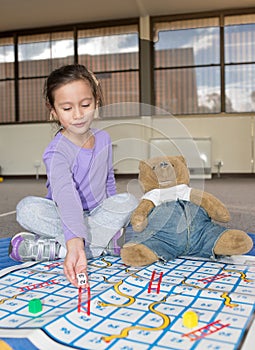 Girl Playing Snakes and Ladders with Teddy Bear.