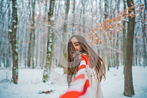 Girl playing with snow in park. Women in winter clothes. Portrait of a beautiful woman dressed a coat.