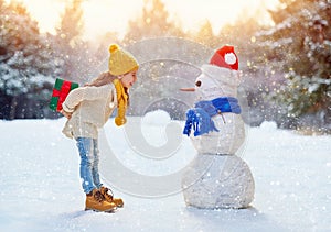 Girl playing with a snowman
