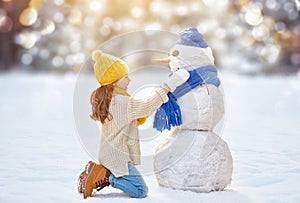 Girl playing with a snowman