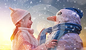 Girl playing with a snowman