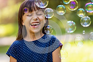 Girl playing with soap bubbles outdoors