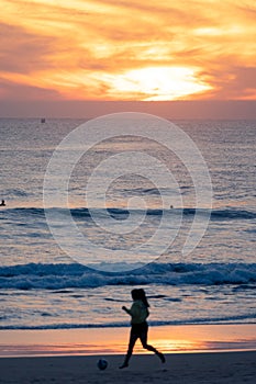 Girl playing soccer at sunset, Carcavelos beach, Lisbon, Portugal