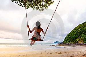 Girl playing the swing on beach