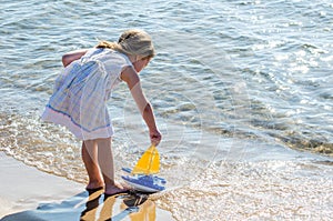 Girl playing with toy sailboat at the lake