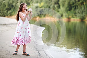 Girl playing with a toy sailing ship by the river