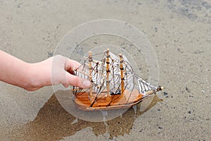 Girl playing with a toy sailing ship by the river