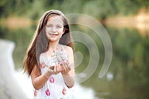 Girl playing with a toy sailing ship by the river