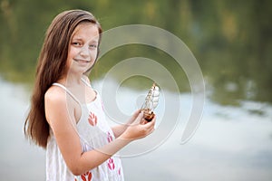 Girl playing with a toy sailing ship by the river