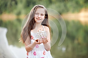 Girl playing with a toy sailing ship by the river