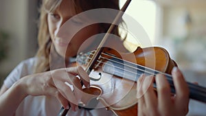 Girl playing violin at home. Violinist playing chords on musical instrument