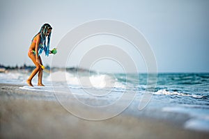 Girl playing with waves kicking and spinning under the summer sun enjoying the vacation