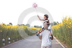 Girl playing with wind turbine and riding on father`s shoulders