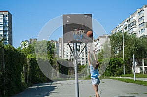 The girl plays basketball on the street.