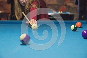 A girl plays a billiard at the club