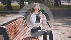 A girl plays the clarinet in the park.