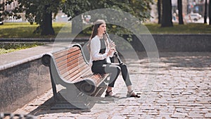 A girl plays the clarinet in the park.