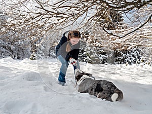 A girl plays with a corgi dog in a snowy forest. Sunlight. Winter`s tale