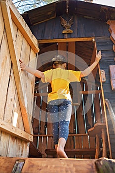 Girl plays in creative handmade treehouse in backyard, summer activity, happy childhood, cottagecore