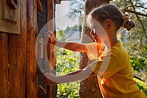 Girl plays in creative handmade treehouse in backyard, summer activity, happy childhood, cottagecore