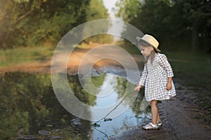 A girl plays in a large and dirty pool of water after the rain.