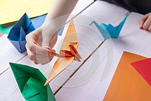 A girl plays with an origami toy that she made herself. Origami crane made of colored paper