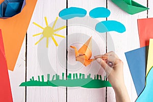 A girl plays with an origami toy that she made herself. Origami crane made of colored paper