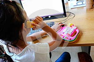 Girl plays a phone and toy with computer.