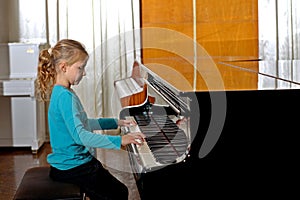 The girl plays piano, close up , white and black keyboard black with white keys in the concert hall