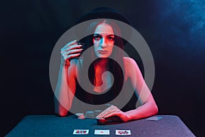 girl plays poker at a table with cards and chips in a casino