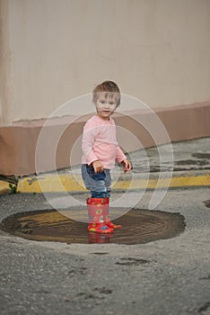 Girl plays in the puddle outdoors