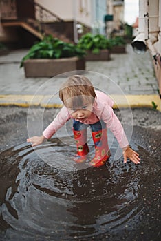 Girl plays in the puddle outdoors