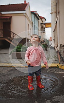 Girl plays in the puddle outdoors