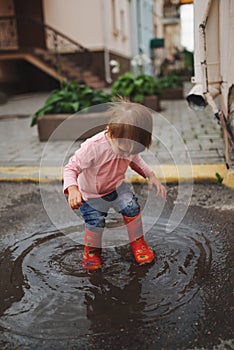 Girl plays in the puddle outdoors