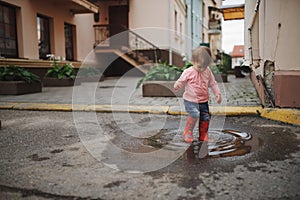 Girl plays in the puddle outdoors