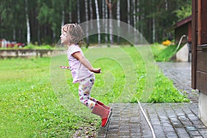 Girl plays in rainy weather Child jumping in puddle and mud in the rain.