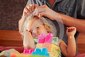 girl plays toy constructor father brushes her hair closeup