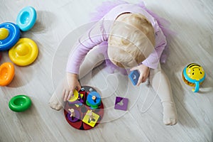 girl plays toys in living room. Montessori wooden toy folded pyramid. Circle, quadra, triangle, rectangle wooden elements of photo