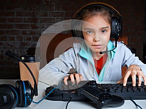 A girl plays a video game while sitting in front of a monitor. She carefully looks at the screen.