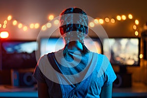 A girl plays video games at a computer. on the background of three monitors. Creative light