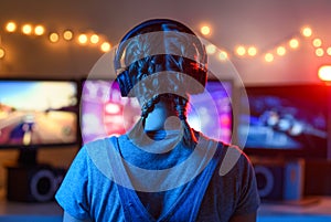 A girl plays video games at a computer. on the background of three monitors. Creative light