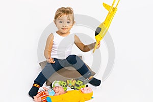 The girl plays with a yellow plane and looks at the camera. Gender stereotypes