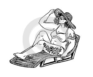 Girl plus size in bikini and hat with tattoos sitting on chair and sunbathing
