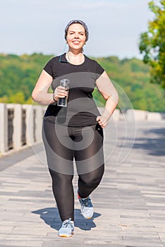 girl plus size with a bottle of water during a morning jog