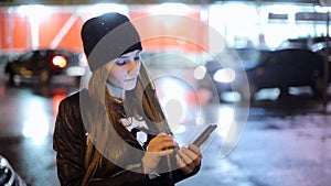 Girl pointing finger on screen smartphone on background illumination bokeh color light in night atmospheric city